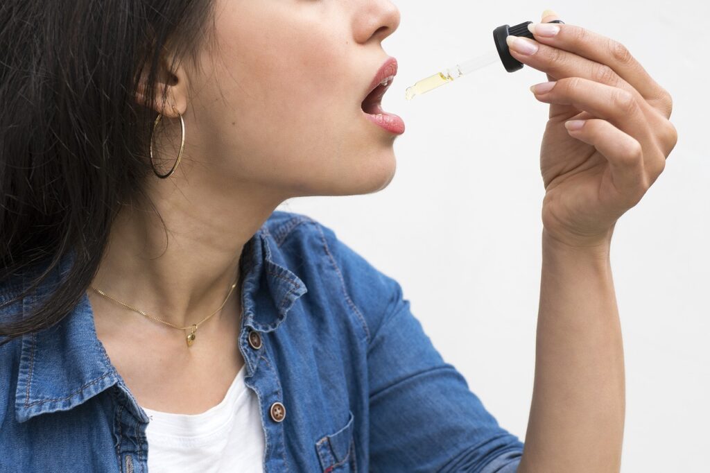 Femme utilisant une pipette d’huile de CBD, étape essentielle pour doser son miel au CBD.
