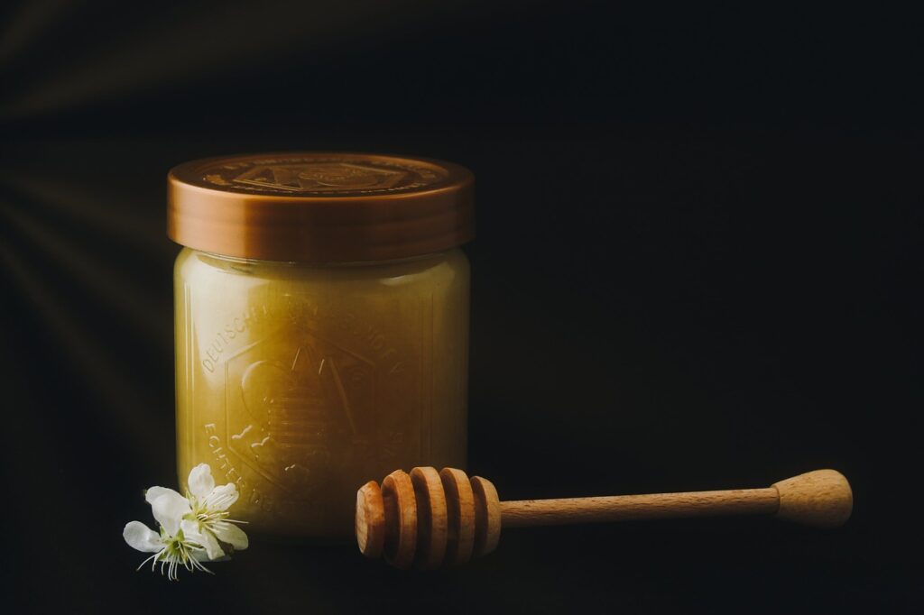 Pot de miel avec une cuillère en bois, parfait pour préparer un miel au CBD maison.