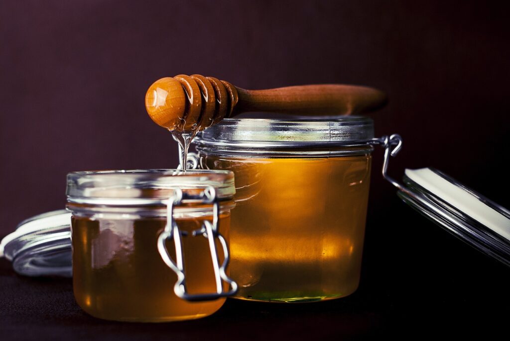Deux pots de miel artisanal avec une cuillère en bois, symbolisant un produit naturel et sain.