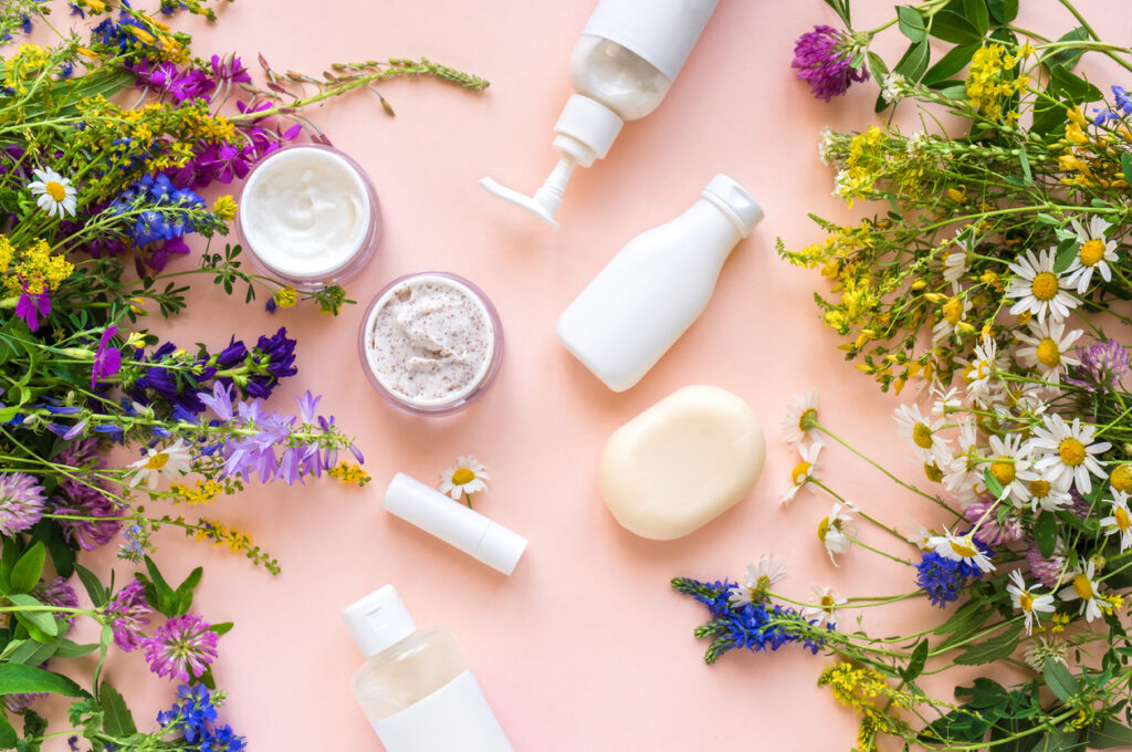 Produits cosmétiques naturels comme des crèmes et savons artisanaux entourés de fleurs