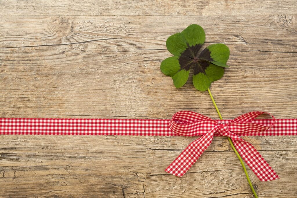 Trèfle à quatre feuilles posé sur un ruban rouge symbolisant la chance et les vœux de bien-être